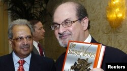 سلمان رشدی در سال ۱۹۸۸ و در حالی که یک نسخه از کتاب «آیات شیطانی» را در دست دارد.