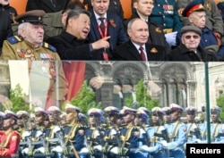 Президент России Владимир Путин и глава Китая Си Цзиньпин наблюдают за прохождением колонны китайских военнослужащих (внизу) на военном параде в Москве, 9 мая 2025 года
