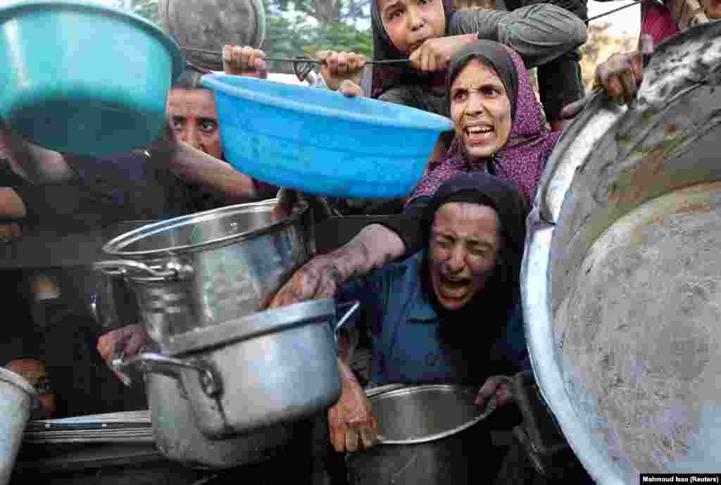 Palestinezë të uritur duke zgjatur enët për të marrë ushqim nga një kuzhinë popullore, më 14 korrik.