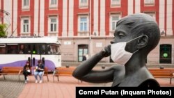 Masca de unică folosință pusă pe fața unei statui din Timișoara