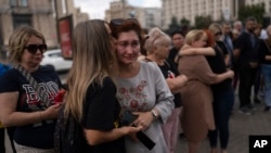 Family members and supporters comfort one another as they gather on Kyiv's Maidan on July 29 to mark the first anniversary of the attack on a prison building in Olenivka in Russian-occupied Ukraine that killed dozens of Ukrainian military prisoners. 