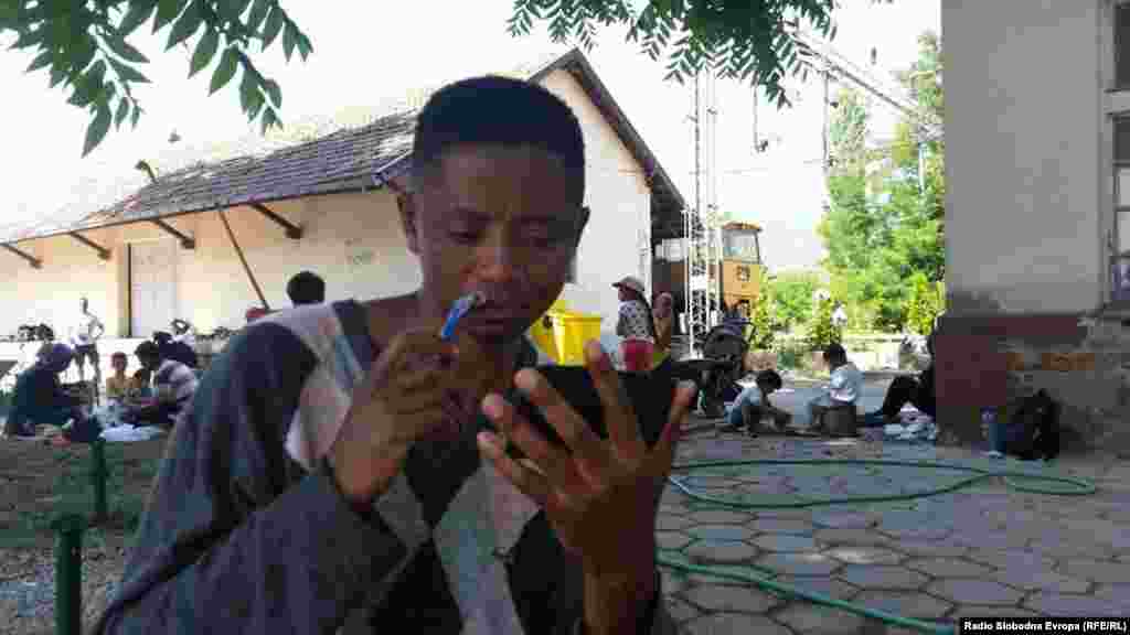 Мигрант од Сиера Леоне се бричи на железничката станица во Демир Капија.