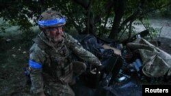 Український військовослужбовець 60-ї окремої механізованої бригади готує снаряди для важкого бойового безпілотника перед польотом над позиціями російських військ e Донецькій області, Україна, 20 травня 2024 року