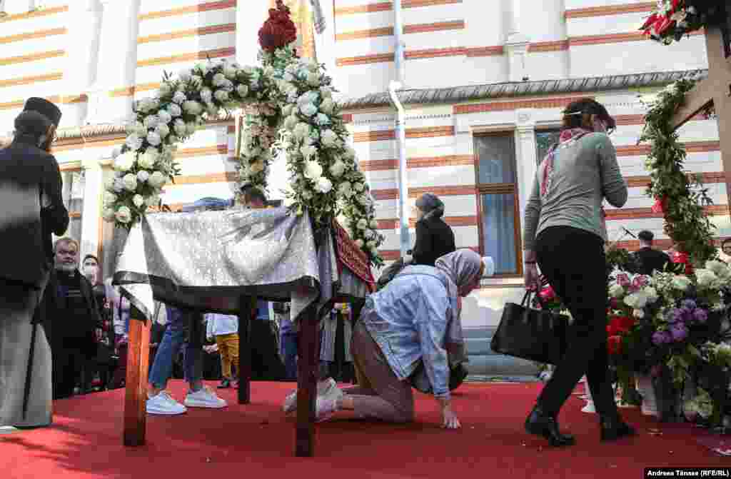 Credincioși ortodocși trec pe sub masă cu ocazia slujbei religioase din Vinerea Mare, la Mănăstirea Radu Vodă din București, Rom&#226;nia. Gestul simbolizează intrarea &#238;n morm&#226;nt și &#238;nvierea sufletului credinciosului, &#238;n același timp cu &#206;nvierea M&#226;ntuitorului.