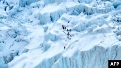 Na ovoj fotografiji snimljenoj 2. maja 2021. planinari putuju duž glečera Khumbu u blizini baznog kampa Everesta u regiji Mount Everest u okrugu Solukhumbu, nekih 140 km sjeveroistočno od glavnog grada Nepala Katmandua.