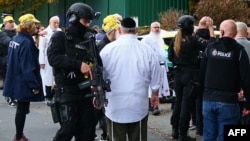 Рабин Деніел Вокер (у центрі праворуч) стоїть серед озброєних поліцейських, які розмовляють з членами єврейської громади біля синагоги єврейської громади Хітон-Парк, північний Манчестер, 2 жовтня 2025 року, після нападу на синагогу