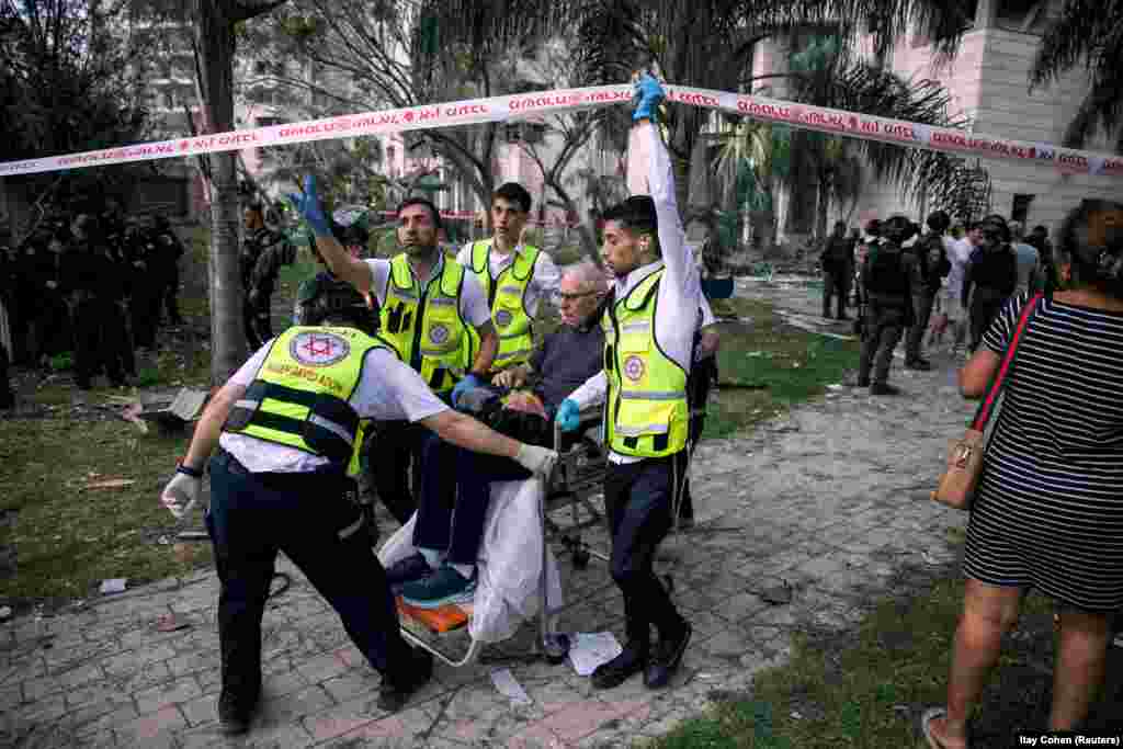 Personeli i shpëtimit duke evakuuar një burrë nga një ndërtesë e sulmuar nga një raketë iraniane, në Izraelin qendror, më 16 qershor.