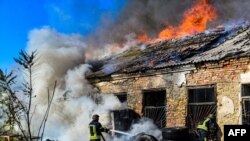 Ukrán tűzoltók küzdenek a lángokkal egy orosz tüzérségi támadás után Herszonban 2023. szeptember 19-én