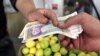 An Iranian man pays a grocer with 50,000-rial banknotes at a shop in Tehran on October 3.