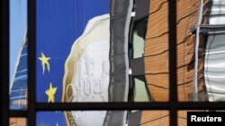 Reflektimi i monedhës së euros në fasadën e ndëstesës së Komisionit Evropian në Bruksel...