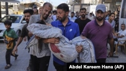 În imagine, rude ale unuia din cei şase copii care au murit în urma unui atac israelian asupra unui punct de alimentare cu apă, îi cară corpul neînsufleţit, pentru înmormântare, duminică, 13 iulie 2025.