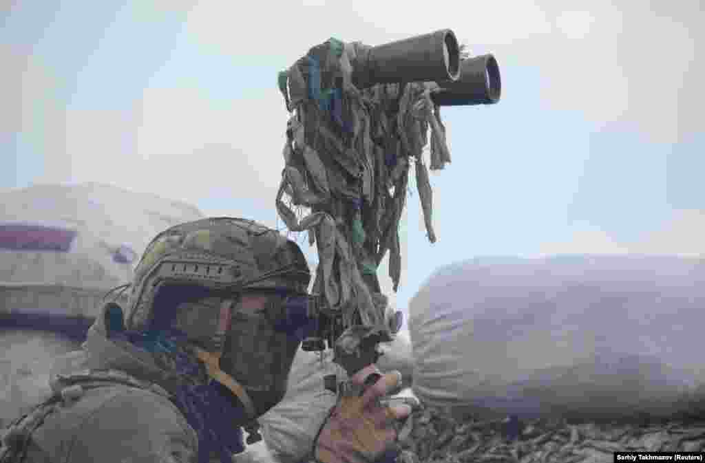 Egy ukrán katona figyeli távcsővel a szeparatisták pozícióit április 6-án Donyeckhez közel. A város a Moszkva által támogatott szakadárok ellenőrzése alatt áll. &nbsp;