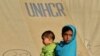 An internally displaced girl carries a child at a makeshift tent camp in Swabi.