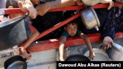 Një fëmijë mban një tenxhere ndërsa palestinezët mblidhen për të marrë ushqim nga një kuzhinë bamirësie, në Qytetin e Gazës, 22 korrik 2025.