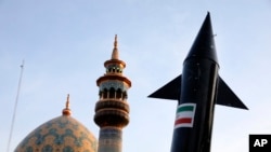 Një model i një rakete bartet nga demonstratorët iranianë, në prapavijën e saj shihet minarja e një xhamie, gjatë një tubimi kundër Izraelit në Teheran, 15 prill 2024.