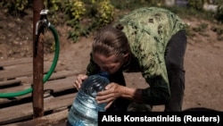 Žena pije čistu vodu iz kanistera koji je upravo napunila u istočno-ukrainskm gradu Slavjansku. 7. avgust 2022. 