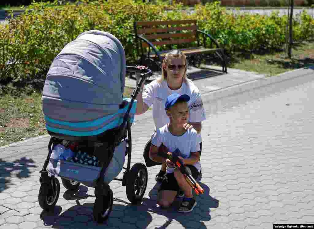 Момче со пушка играчка со својата мајка за време на погреб на украински војник во регионот Киев на 17 јули.