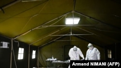 Punonjësit shëndetësorë të veshur me kostume mbrojtëse punojnë brenda një tende të ngritur për pacientët e dyshuar COVID-19 jashtë Qendrës së Mjekësisë Familjare në Prishtinë më 6 prill 2020. 