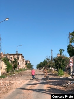 Жінки йдуть розбитою вулицею Маріуполя, 2022 рік