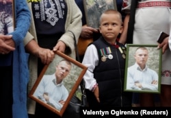 Hozzátartozók egy, a kelet-ukrajnai konfliktusban elesett ukrán katona portréját tartják az ilovajszki csata hatodik évfordulója alkalmából tartott megemlékezésen, az Ukrajna védelmezőinek emléknapja előtt