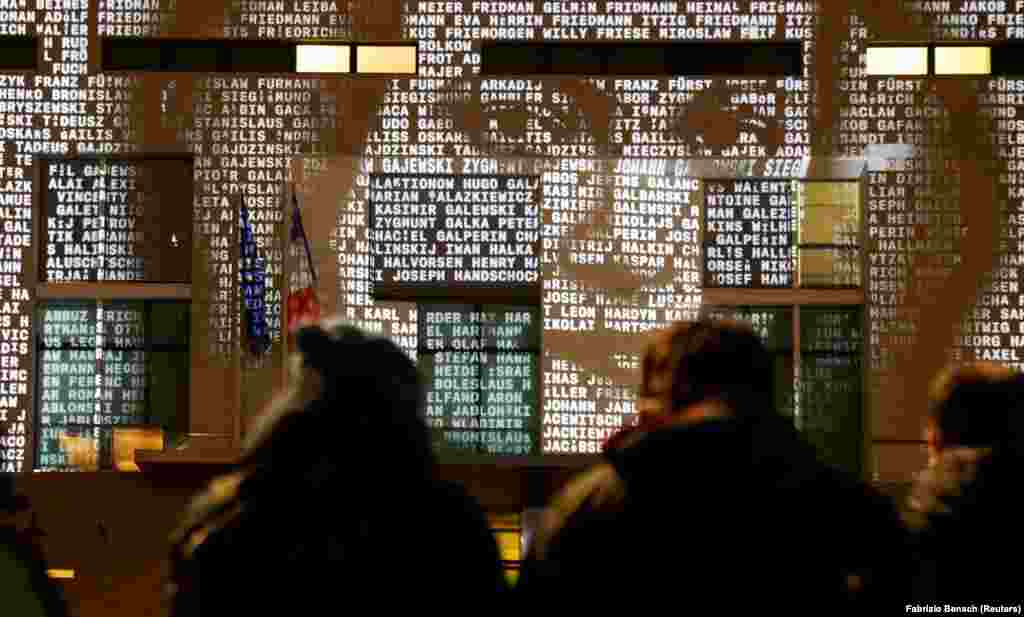 Njerëzit shikojnë një instalacion dritash të quajtur #everynamecounts, me emrat e viktimave të regjimit nazist që shfaqen në muret e Ambasadës franceze, për të kujtuar viktimat para Ditës Përkujtimore të Holokaustit në Berlin, Gjermani, 22 janar 2021.