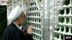 Iranian President Hassan Rohani kisses a religious shrine while visiting the holy city of Qom on February 25.