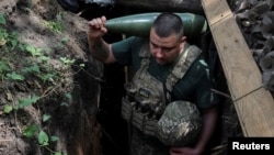 Військовослужбовець 30-ї ОМБр ЗСУ імені князя Костянтина Острозького несе снаряд до самохідної гаубиці 2С1 «Гвоздика», Донецька область, 13 серпня 2025 року