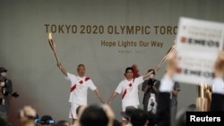 Purtătorii de torțe din Tokyo pozează în timpul unei ceremonii de iluminare, 9 iulie 2021.