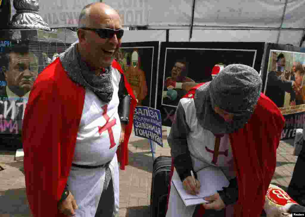 Ukraine - England soccer fans walk near signboards put up by supporters of jailed opposition leader Yulia Tymoshenko in Kyiv, 14Jun2012