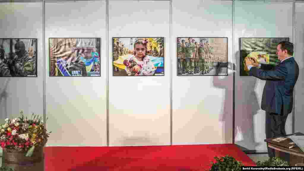 Чоловік перефотографовує роботи переможців фотоконкурсу перед початком церемонії відкриття