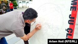 Një protestues vendos mbishkrim në një pano të ish-krerëve të UÇK-së që po gjykohen në Hagë.