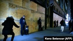 Gărzile private de securitate stau în afara magazinului universal Saks Fifth Avenue, cu o noapte înainte de alegerile prezidențiale din New York, 2 noiembrie 2020.