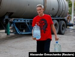 Чоловік несе воду, розлиту з автоцистерни, Донецьк, 21 серпня 2025 року