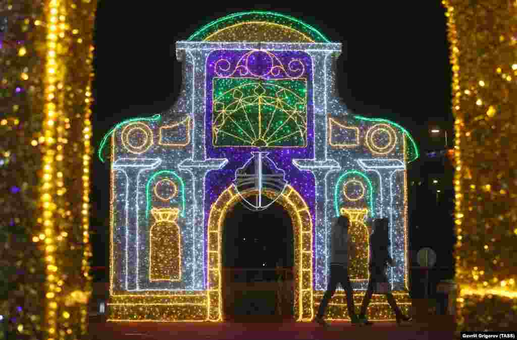 Луѓе покрај светлечка инсталација пред железничката станица Кијевски во Москва.