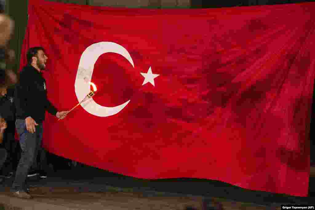  Un bărbat se pregătește să dea foc steagului național turc, în timpul unei demonstrații care marchează 106 ani de la masacrul împotriva armenilor, în onoarea victimelor genocidului armean, Erevan, Armenia. Armenii au marcat comemorarea celor 1,5 milioane de armeni uciși de către turcii otomani, eveniment considerat de către comunitatea istoricilor din întreaga lume drept genocid, deși Turcia respinge afirmația.