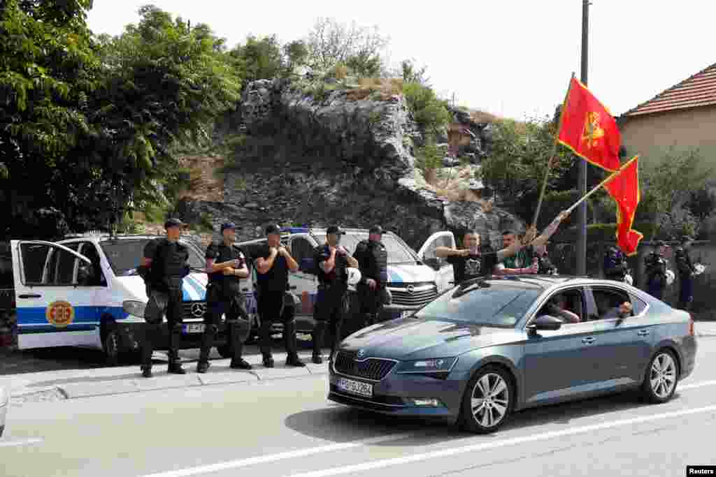 Луѓе со црногорски знамиње поминуваат покрај полициски контролен пункт на влезот во Цетиње. &nbsp;