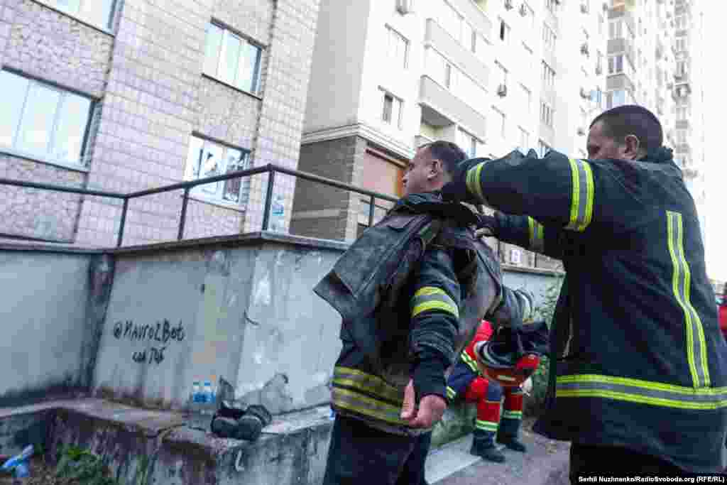 Один із пожежників допомагає своєму побратиму зняти бронежилет після гасіння пожежі внаслідок влучання російського «Шахеда». Київ, 30 травня 2023 року