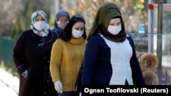 Disa gra me maska mbrojtëse duke ecur në rrugët e Shkupit. 