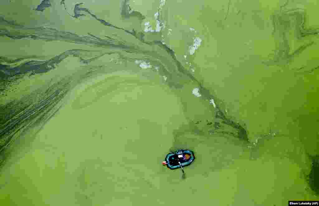 Ukrajinski ribar u gumenom čamcu usred zelenih algi u rezervoaru u Kijevu. (AP / Efrem Lukatski)