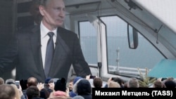 Люди, наблюдающие за трансляцией запуска железнодорожного движения по Керченскому мосту.