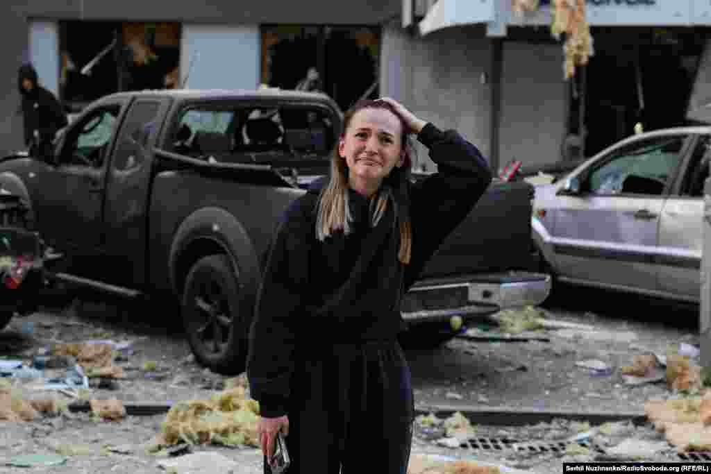 Дівчина плаче біля пошкодженої будівлі у Києві