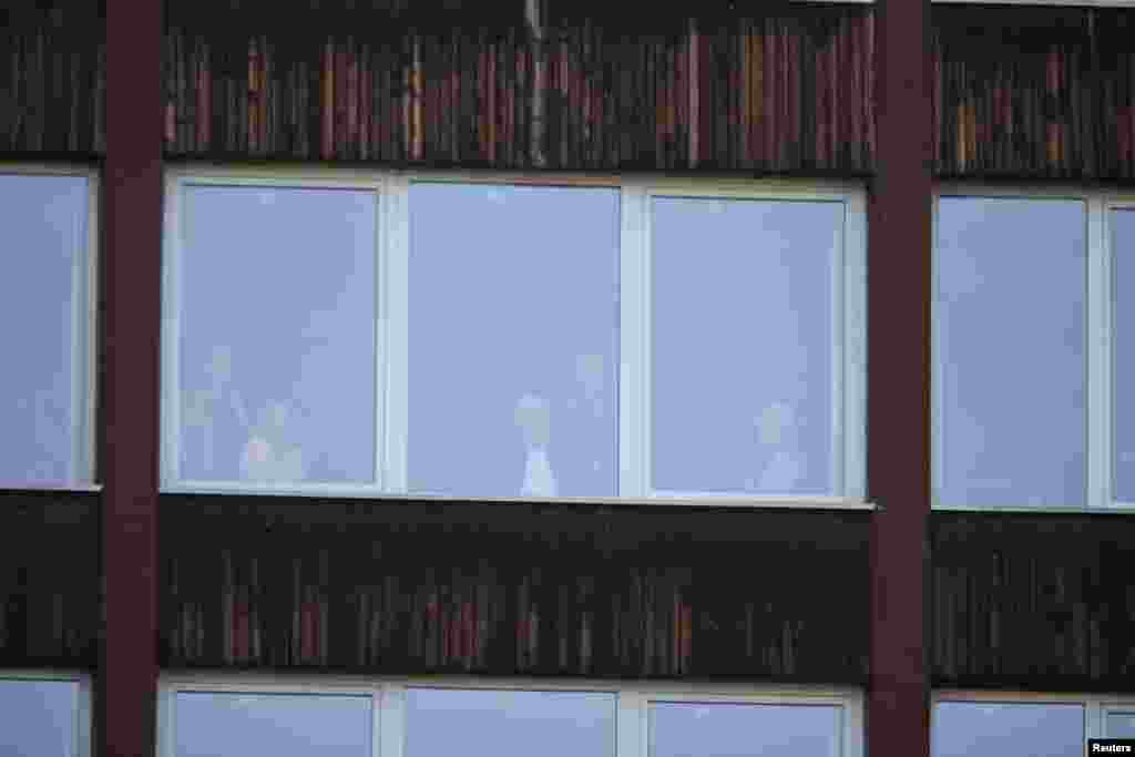 Ljudi gledaju kroz prozore u neoštećenom dijelu zgrade nakon požara u Domu penzionera u Tuzli, Bosna i Hercegovina, 5. novembra 2025.