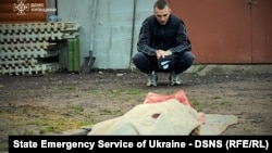 Чоловік біля тіла жінки, яка загинула під час удару російського безпілотника в Київській області, 18 травня 2025 року