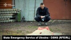 Një burrë duke shikuar trupin e një gruaje të vrarë gjatë një sulmi me dron rus në rajonin e Kievit më 18 maj.