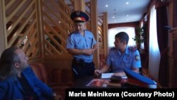 Полицейские составляют протокол на украинского журналиста Александра Гороховского (слева) во время встречи в рамках проекта "Школа журналистики" в гостинице Уральска, 15 сентября 2018 года.