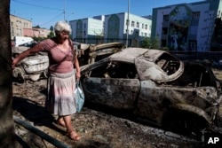 Місцева жителька проходить повз автомобілі, знищені російським ударом. Київ, Україна, 4 липня 2025 року