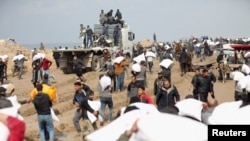 Palestinci nose vreće brašna koje su zgrabili iz kamiona pomoći u blizini izraelskog kontrolnog punkta, dok se stanovnici Gaze suočavaju sa kriznim nivoom gladi, usred sukoba između Izraela i Hamasa, u gradu Gazi, 19. februara 2024. 