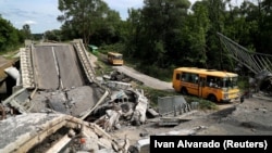 Un convoi cu refugiați din orașul Kupiansk, ocupat de trupele rusești, pe un drum avariat la periferia orașului Harkov, 30 mai 2022