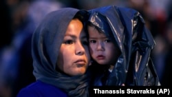 FILE: An Afghan woman holds her child upon their arrival from Lesbos island to the port of Piraeus, near Athens in October 2019.