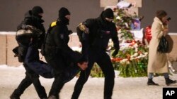 Полицаи задържат мъж, който полага цветя в памет на Алексей Навални върху Мемориала на жертвите на политическите репресии в Санкт Петербург, Русия в петък, 16 февруари 2024 г.